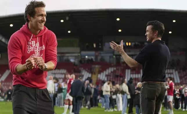 Wrexham co-owners Ryan Reynolds, left, and Rob McElhenney celebrate at the end of the English League One soccer match between Wrexham and Charlton Athletic at the Racecourse ground in Wrexham, Wales, Saturday, April 26, 2025. (AP Photo/Jon Super)