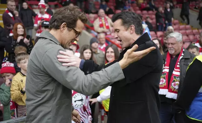 Wrexham co-owners Ryan Reynolds, left, and Rob McElhenney, right, speak before the English League One soccer match between Wrexham and Charlton Athletic at the Racecourse ground in Wrexham, Wales, Saturday, April 26, 2025. (AP Photo/Jon Super)