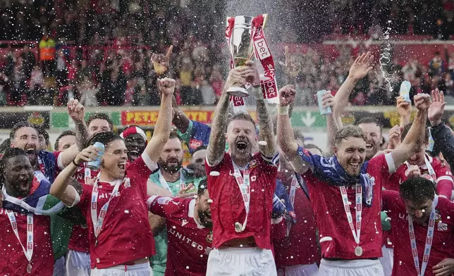 Wrexham's James McClean rises the trophy as they win the English League One soccer match between Wrexham and Charlton Athletic at the Racecourse ground in Wrexham, Wales, Saturday, April 26, 2025. (AP Photo/Jon Super)