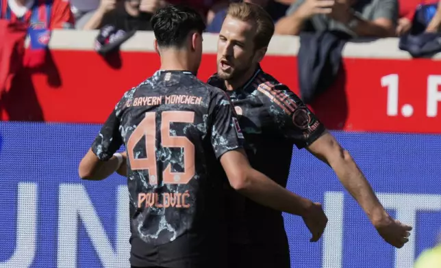 Bayern's Aleksandar Pavlovic and Harry Kane celebrate after a goal during the German Bundesliga soccer match between Heidenheim and Bayern Munich in Heidenheim, Germany, Saturday, April 19, 2025. (AP Photo/Matthias Schrader)
