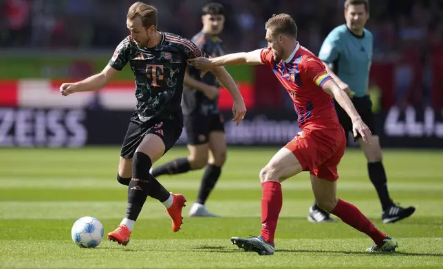 Heidenheim's Patrick Mainka guards Bayern's Harry Kane during the German Bundesliga soccer match between Heidenheim and Bayern Munich in Heidenheim, Germany, Saturday, April 19, 2025. (AP Photo/Matthias Schrader)