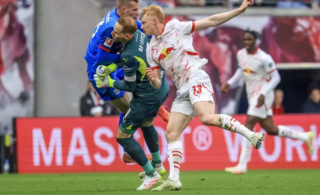 Leipzig goalkeeper Peter Gulacsi, center, and Kiel's David Zec, left, collide during the German Bundesliga soccer match between RB Leipzig and Holstein Kiel, at the Red Bull Arena in Leipzig, Germany, Saturday, April 19, 2025. (Jan Woitas/dpa via AP)