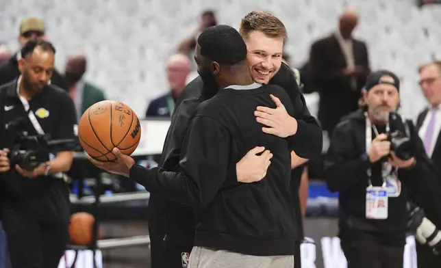 Los Angeles Lakers' Luka Doncic, center right, hugs his former coach, Dallas Mavericks assistant coach God Shammgod, center left, during team warmups before an NBA basketball game in Dallas, Wednesday, April 9, 2025. (AP Photo/LM Otero)