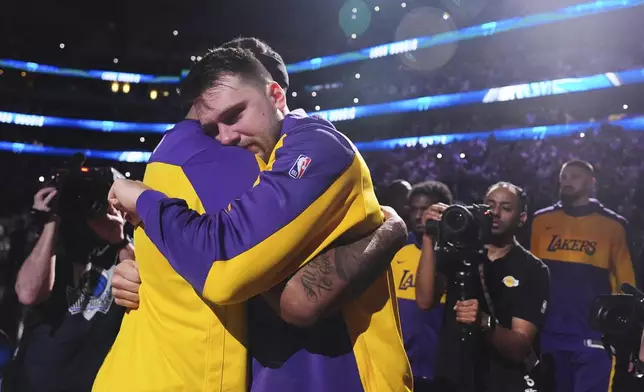 Los Angeles Lakers' Luka Doncic, center right, hugs Markieff Morris, center left, during team introductions before an NBA basketball game against the Dallas Mavericks in Dallas, Wednesday, April 9, 2025. (AP Photo/LM Otero)