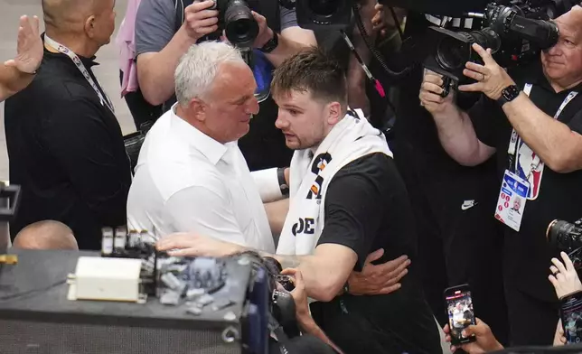 Sasa Doncic, center left in white, hugs his son, Los Angeles Lakers' Luka Doncic, center right, after the team's NBA basketball game against the Dallas Mavericks in Dallas, Wednesday, April 9, 2025. (AP Photo/Julio Cortez)