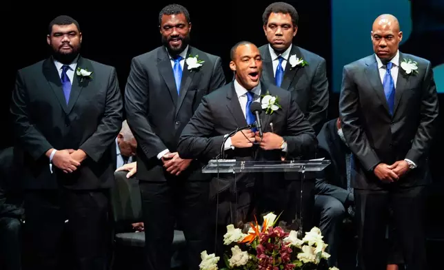 George Foreman IV, center, stands with his brothers as he delivers the eulogy for his father during a memorial service for Olympic and world champion boxer and minister George Foreman at Wortham Theater Center in Houston, Monday, April 14, 2025. (Brett Coomer/Houston Chronicle via AP)