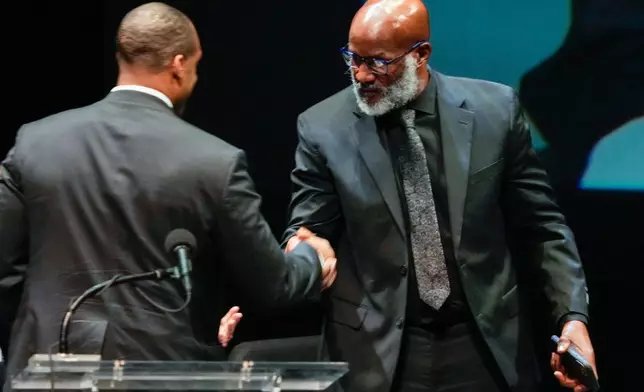 Michael Moorer, former world champion boxer shakes hands with George Foreman IV as he gets up to speak about the boxing career of Olympic and world champion boxer and minister George Foreman at Wortham Theater Center in Houston, Monday, April 14, 2025. (Brett Coomer/Houston Chronicle via AP)