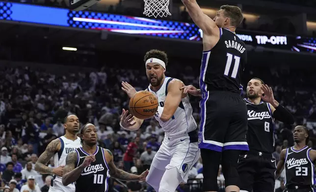 Dallas Mavericks guard Klay Thompson, center, passes the ball while defended by Sacramento Kings center Domantas Sabonis (11) during the first half of an NBA play-in tournament basketball game Wednesday, April 16, 2025, in Sacramento, Calif. (AP Photo/Godofredo A. Vásquez)