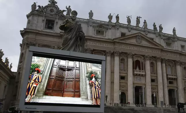 FILE - A giant monitor in St. Peter's Square at the Vatican, Tuesday, March 12, 2013 shows the heavy wooden door to the Sistine Chapel being closed and locked, signaling the start of the conclave to elect a new pope to succeed Benedict XVI following his stunning resignation. (AP Photo/Gregorio Borgia, File)