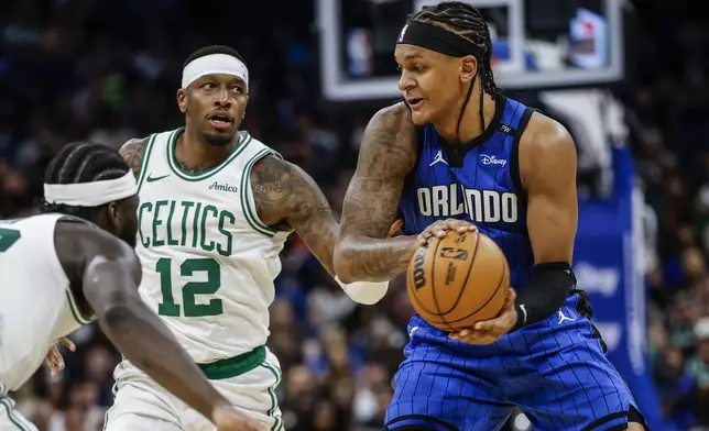 Orlando Magic forward Paolo Banchero, right, is defended by Boston Celtics forward Torrey Craig (12) during the second half of an NBA basketball game, Wednesday, April 9, 2025, in Orlando, Fla. (AP Photo/Kevin Kolczynski)
