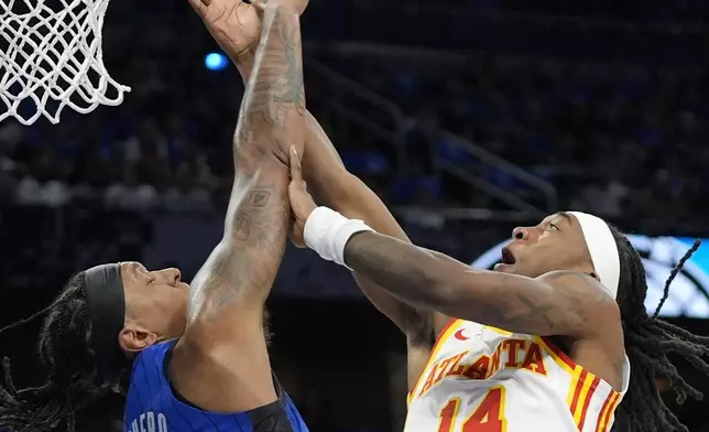 Orlando Magic forward Paolo Banchero (5) blocks a shot attempt by Atlanta Hawks guard Terance Mann (14) during the first half of an NBA play-in tournament basketball game, Tuesday, April 15, 2025, in Orlando, Fla. (AP Photo/John Raoux)