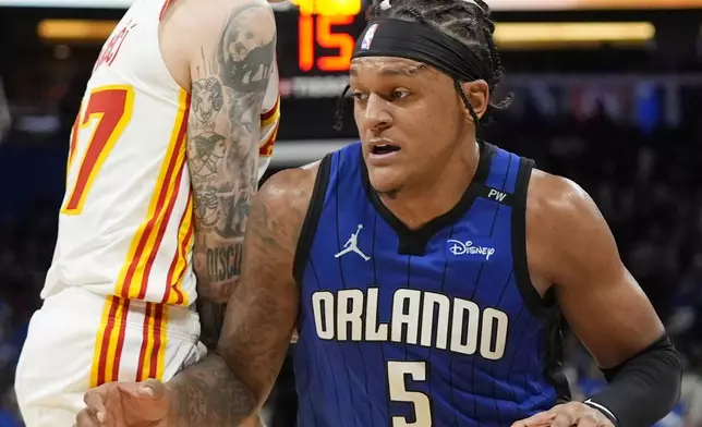 Orlando Magic forward Paolo Banchero (5) drives around Atlanta Hawks guard Vit Krejci, left, during the second half of an NBA play-in tournament basketball game, Tuesday, April 15, 2025, in Orlando, Fla. (AP Photo/John Raoux)