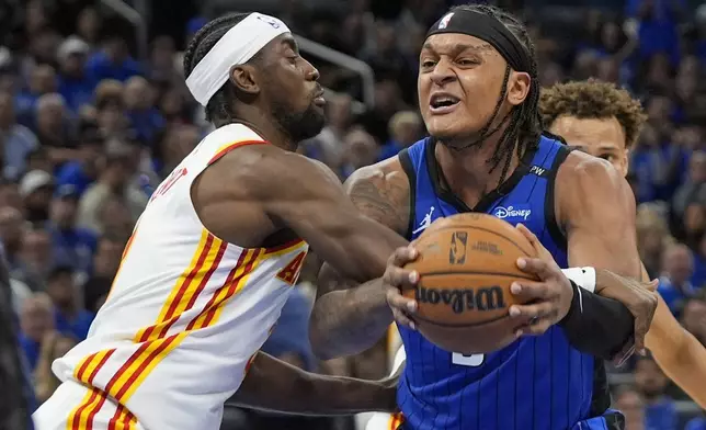 Orlando Magic forward Paolo Banchero, right, is fouled by Atlanta Hawks guard Caris LeVert, left, as he goes up for a shot during the second half of an NBA play-in tournament basketball game, Tuesday, April 15, 2025, in Orlando, Fla. (AP Photo/John Raoux)