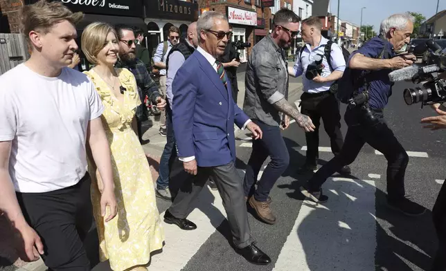Reform UK leader Nigel Farage crosses the road with Reform UK mayoral candidate Andrea Jenkyns as they campaign together in Scunthorpe, England, Tuesday, April 29, 2025. (AP Photo/Darren Staples)