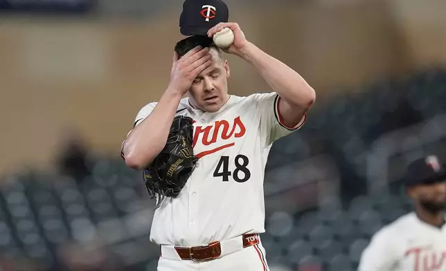 Minnesota Twins relief pitcher Justin Topa (48) adjusts his cap after committing a throwing error which resulted in a run scored during the sixth inning of a baseball game against the New York Mets, Monday, April 14, 2025, in Minneapolis. (AP Photo/Abbie Parr)