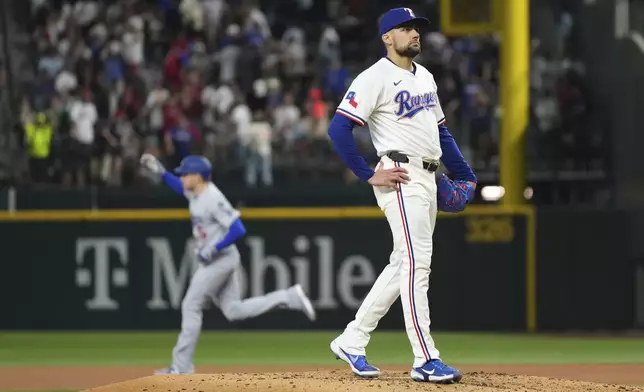 Texas Rangers starting pitcher Nathan Eovaldi stands on the mound after giving up a two run home run to Los Angeles Dodgers' Freddie Freeman, rear, that scored Mookie Betts during the fourth inning of a baseball game Saturday, April 19, 2025, in Arlington, Texas. (AP Photo/Jeffrey McWhorter)
