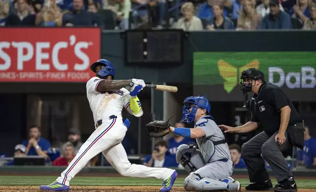 Texas Rangers' Adolis García follows through on a walk-off two run home run that scored Josh Smith off of Los Angeles Dodgers pitcher Kirby Yates during the ninth inning of a baseball game Saturday, April 19, 2025, in Arlington, Texas. (AP Photo/Jeffrey McWhorter)