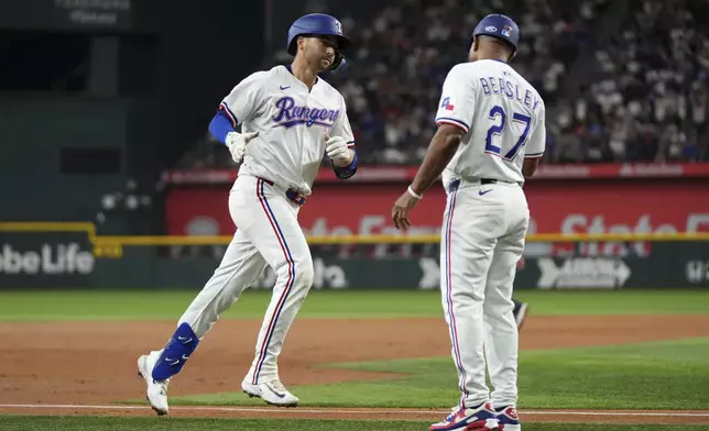 Texas Rangers' Kyle Higashioka is congratulated by third base coach Tony Beasley after hitting a two-run home run that scored Dustin Harris during the third inning of a baseball game against the Los Angeles Dodgers, Saturday, April 19, 2025, in Arlington, Texas. (AP Photo/Jeffrey McWhorter)