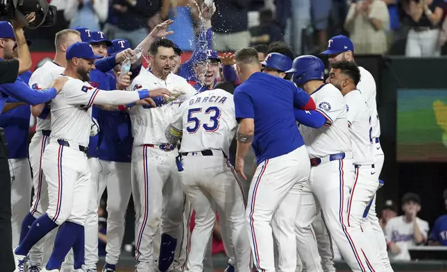 Texas Rangers' Adolis García is mobbed at home plate after hitting a walk-off two run home run that scored Josh Smith off of Los Angeles Dodgers pitcher Kirby Yates during the ninth inning of a baseball game Saturday, April 19, 2025, in Arlington, Texas. (AP Photo/Jeffrey McWhorter)
