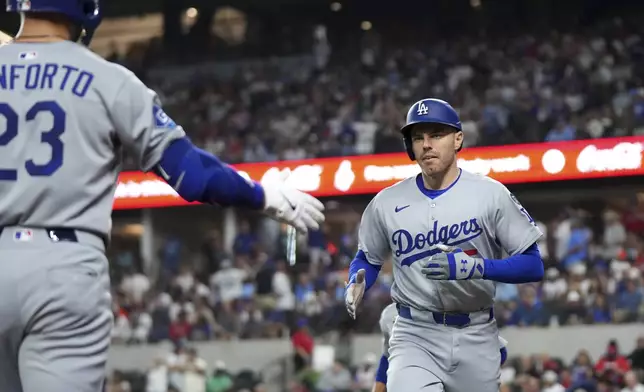Los Angeles Dodgers' Freddie Freeman is congratulated by Michael Conforto (23) after hitting a two run home run that scored Mookie Betts off of Texas Rangers pitcher Nathan Eovaldi during the fourth inning of a baseball game Saturday, April 19, 2025, in Arlington, Texas. (AP Photo/Jeffrey McWhorter)