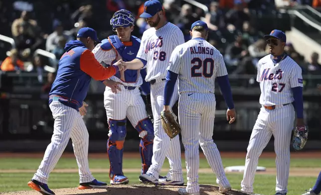 New York Mets manager Carlos Mendoza, left, takes the ball from pitcher Tylor Megill (38) during the fifth inning of a baseball game against the Miami Marlins, Wednesday, April 9, 2025, in New York. (AP Photo/Pamela Smith)