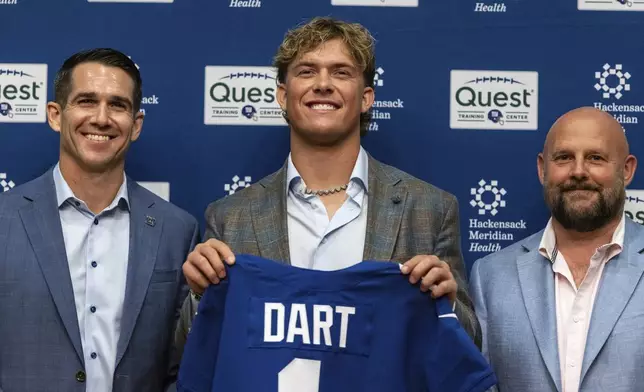 New York Giants first-round draft pick Jaxson Dart, center, holds up a shirt with general manager Joe Schoen, left, and head coach Brian Daboll, right, at a news conference at the NFL football team's training center in East Rutherford, N.J., Friday, April 25, 2025. (AP Photo/Stefan Jeremiah)