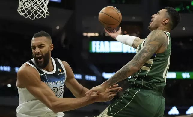 Milwaukee Bucks' Kyle Kuzma, right, commits an offensive foul against Minnesota Timberwolves' Rudy Gobert during the first half of an NBA basketball game Tuesday, April 8, 2025, in Milwaukee. (AP Photo/Aaron Gash)