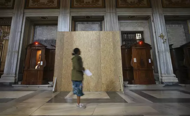 A woman walks past a wooden board where work in progress is taking place on the spot where Pope Francis will be buried, inside St. Mary Major basilica, in Rome, Tuesday, April 22, 2025. (AP Photo/Alessandra Tarantino)