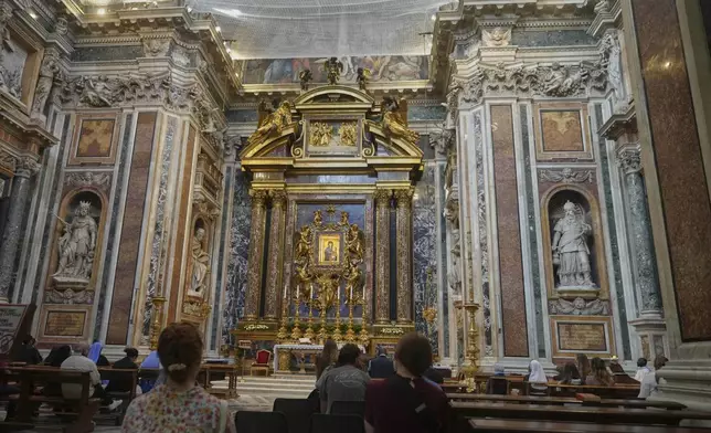 Faithful pray before the Salus populi Romani (Salvation of the people of Rome), a Byzantine-style painting that features an image of Mary, draped in a blue robe, holding the infant Jesus who in turn is holding a jeweled golden book, inside St. Mary Major basilica, where Pope Francis will be buried, in Rome, Tuesday, April 22, 2025. (AP Photo/Alessandra Tarantino)
