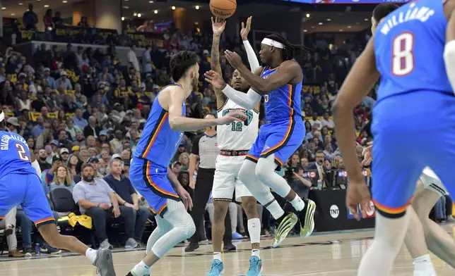 Memphis Grizzlies guard Ja Morant (12) shoots between Oklahoma City Thunder guard Luguentz Dort (5) and forward Chet Holmgren, center left, in the first half of Game 3 of an NBA first-round playoff series Thursday, April 24, 2025, in Memphis, Tenn. (AP Photo/Brandon Dill)