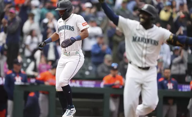 Seattle Mariners center fielder Julio Rodriguez jumps on home plate to score the game-winning run after teammate Randy Arozarena, right, was walked with the bases loaded against the Houston Astros for a 7-6 win in a baseball game Wednesday, April 9, 2025, in Seattle. (AP Photo/Lindsey Wasson)