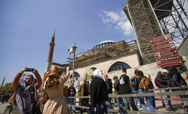 People wait in line to visit Byzantine-era Hagia Sophia mosque next to scaffolds installed for restoration works, in Istanbul, Turkey, Sunday, April 13, 2025. (AP Photo/Emrah Gurel)