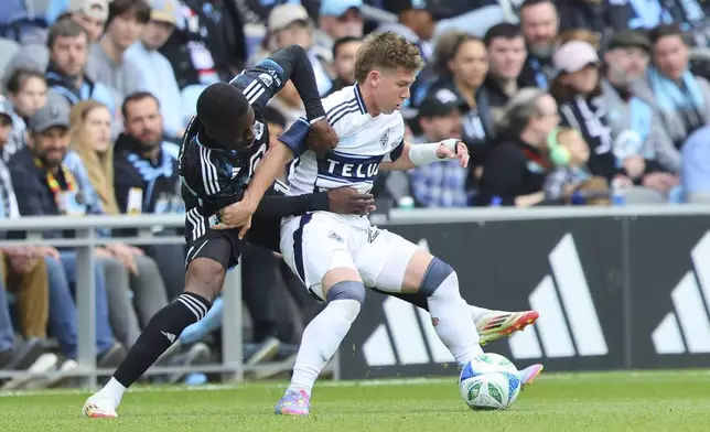 Minnesota United forward Tani Oluwaseyi, left, battles Vancouver Whitecaps defender Tate Johnson, right, during the second half of an MLS soccer match Sunday, April 27, 2025, in St. Paul, Minn. (AP Photo/Adam Bettcher)