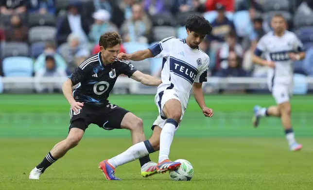 Minnesota United midfielder Wil Trapp, left, pushes Vancouver Whitecaps midfielder Jeevan Badwal during the second half of an MLS soccer match on Sunday, April 27, 2025, in St. Paul, Minn. (AP Photo/Adam Bettcher)