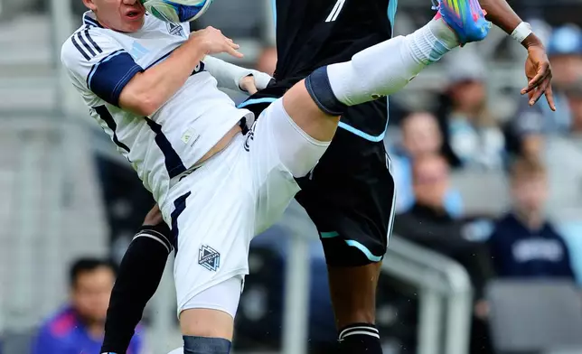 Vancouver Whitecaps defender Tate Johnson, left, takes the ball to his face while Minnesota United forward Kelvin Yeboah (9) defends during the second half of an MLS soccer match on Sunday, April 27, 2025, in St. Paul, Minn. (AP Photo/Adam Bettcher)