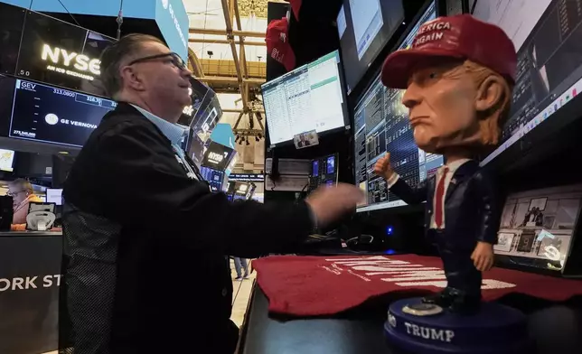 A Donald Trump bobblehead sits on the counter as trader Jonathan Mueller works on the floor of the New York Stock Exchange, Tuesday, April 22, 2025. (AP Photo/Richard Drew)