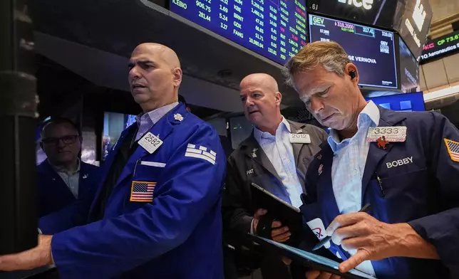 Specialist Philip Finale, left, works with traders Patrick Casey, center, and Robert Charmak on the floor of the New York Stock Exchange, Tuesday, April 22, 2025. (AP Photo/Richard Drew)
