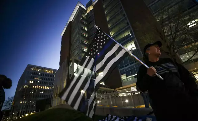 Sally R. of Holland holds a "blue line" flag outside the Kent County Courthouse on the first day of testimony in the 2nd degree murder trial of former Grand Rapids City Police officer Christopher Schurr on April 28, 2025 in Grand Rapids, MI. Schurr shot and killed Congolese immigrant Patrick Lyoya during a traffic stop three years ago. (Chris duMond/Detroit News via AP)