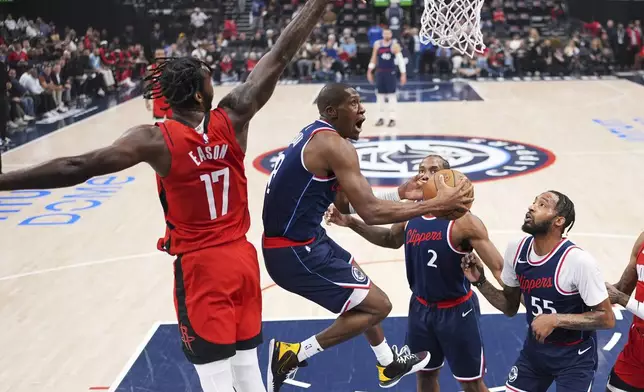 Los Angeles Clippers guard Kris Dunn, second from left, shoots as Houston Rockets forward Tari Eason, left, defends while forward Kawhi Leonard, second from right, and forward Derrick Jones Jr. watch during the first half of an NBA basketball game Wednesday, April 9, 2025, in Inglewood, Calif. (AP Photo/Mark J. Terrill)