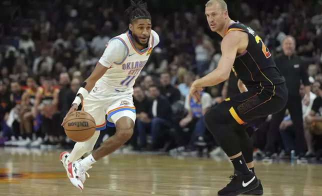Oklahoma City Thunder guard Isaiah Joe (11) drives around Phoenix Suns center Mason Plumlee during the first half of an NBA basketball game, Wednesday, April 9, 2025, in Phoenix. (AP Photo/Rick Scuteri)