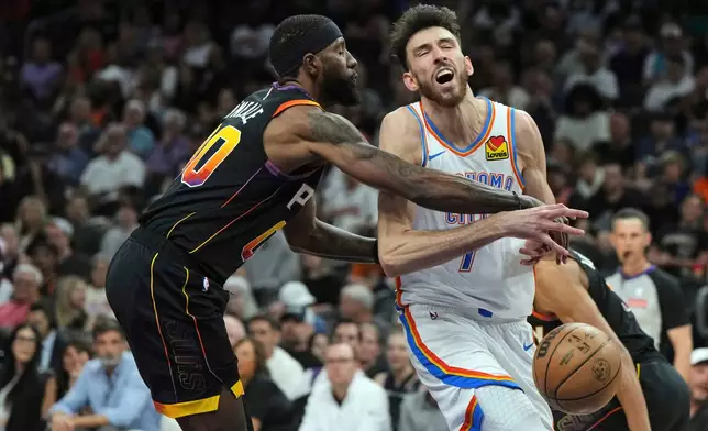 Phoenix Suns forward Royce O'Neale (00) knocks the ball away from Oklahoma City Thunder forward Chet Holmgren during the first half of an NBA basketball game, Wednesday, April 9, 2025, in Phoenix. (AP Photo/Rick Scuteri)