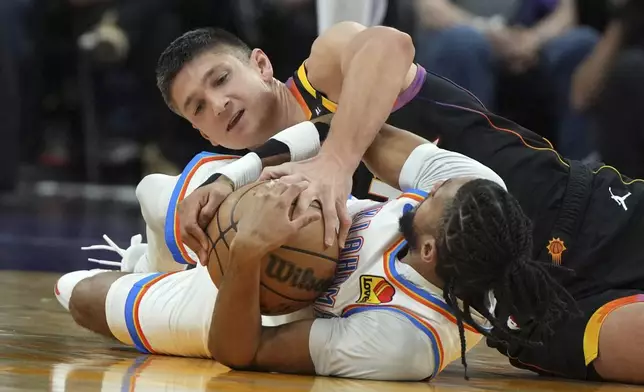 Phoenix Suns guard Grayson Allen (8) fights for the loose ball with Oklahoma City Thunder guard Isaiah Joe during the first half of an NBA basketball game, Wednesday, April 9, 2025, in Phoenix. (AP Photo/Rick Scuteri)