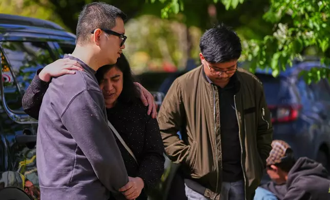 People comfort each other near the scene the day after a driver killed multiple people during a Filipino community festival Sunday, April 27, 2025, in Vancouver, British Columbia. (AP Photo/Lindsey Wasson)