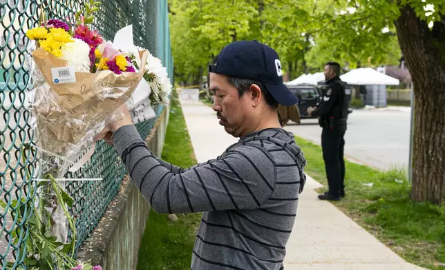 A man leaves flowers on a fence, near the location where a vehicle drove into crowd at a street festival last night, in Vancouver, British Columbia, Sunday April 27, 2025. (Rich Lam/The Canadian Press via AP)