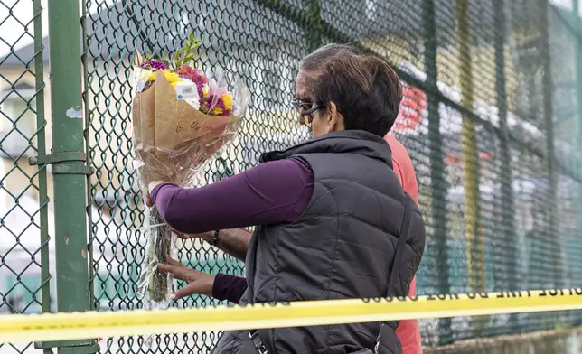 Members of the public attach flowers to a fence, near the scene where a vehicle drove into crowd at a street festival the night before, in Vancouver, Sunday April 27, 2025. (Rich Lam/The Canadian Press via AP)