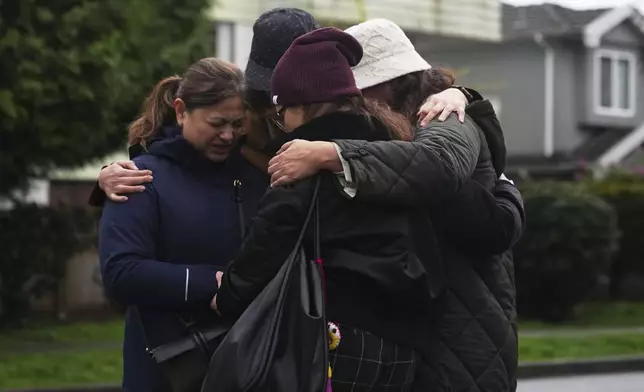 Dimples Lao, left, huddles with Filipino friends near where a vehicle drove into a crowd during a Filipino heritage festival in Vancouver, British Columbia, Monday, April 28, 2025. (AP Photo/Lindsey Wasson)