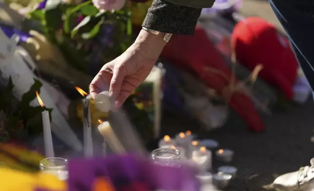 A person lights a candle at a memorial after a vehicle drove into a crowd during a Filipino heritage festival in Vancouver, British Columbia, Sunday, April 27, 2025. (AP Photo/Lindsey Wasson)