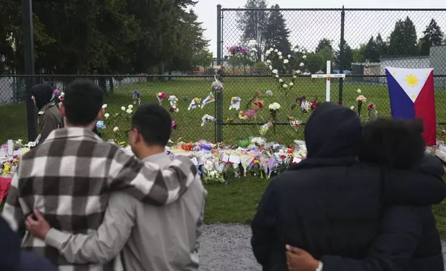 Visitors hug at a memorial for victims after a vehicle drove into a crowd during a Filipino heritage festival in Vancouver, British Columbia, Monday, April 28, 2025. (AP Photo/Lindsey Wasson)