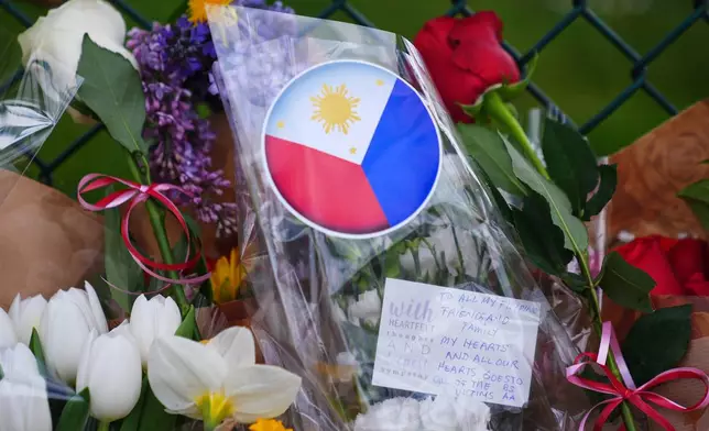 A handwritten note is seen near flowers and the flag of the Philippines at a growing memorial the day after a driver killed multiple people during a Filipino community festival Sunday, April 27, 2025, in Vancouver, British Columbia. (AP Photo/Lindsey Wasson)