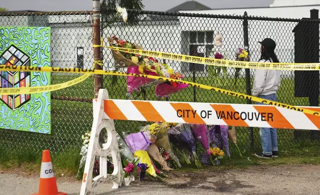 Sarah Edmilao, a member of the Filipino community who says friends had attended earlier in the day, views flowers at a growing memorial near a site the day after a driver killed multiple people during a Filipino festival Sunday, April 27, 2025, in Vancouver, British Columbia. (AP Photo/Lindsey Wasson)